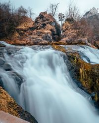 Beautiful view of waterfall in forest against mountains