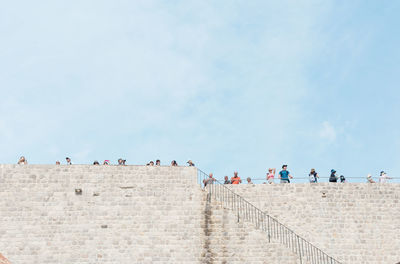 Low angle view of people on observation point against sky