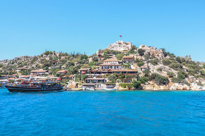 Buildings by sea against blue sky