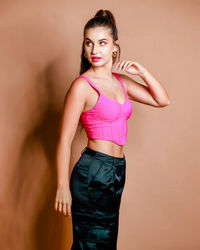 Portrait of young woman standing against yellow background