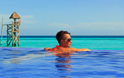 Man smiling in sea against blue sky