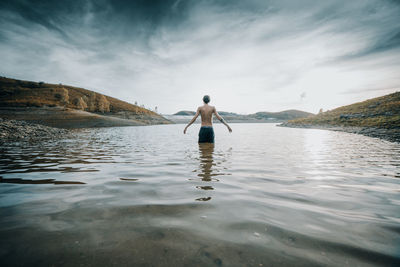 Rear view of man standing in sea against sky