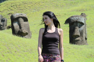 Young woman standing on grass against trees