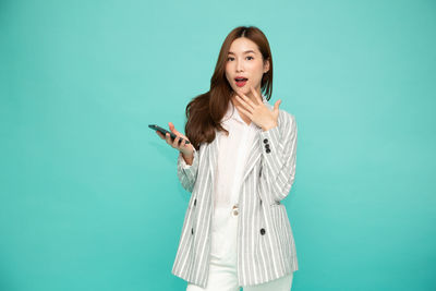 Young woman standing against blue background