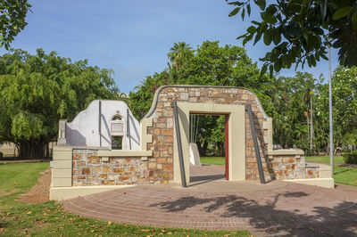 Built structure by trees on field against sky