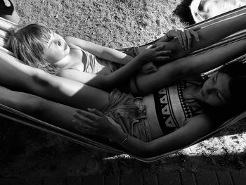 High angle view of sisters lying on hammock at beach