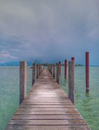 Wooden pier over sea against sky