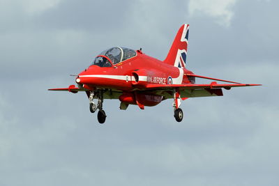 Red airplane flying against sky