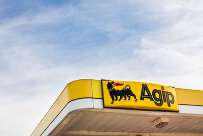 Low angle view of yellow sign against sky