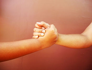 Cropped image of men arm wrestling against wall