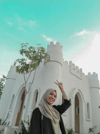 Portrait of smiling young woman standing against building