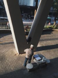 Low section of boy sitting on sidewalk in city