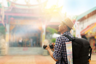 Man holding camera while standing in front of temple