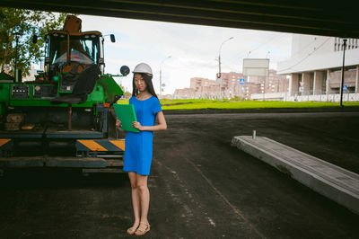 Female architect standing against vehicle