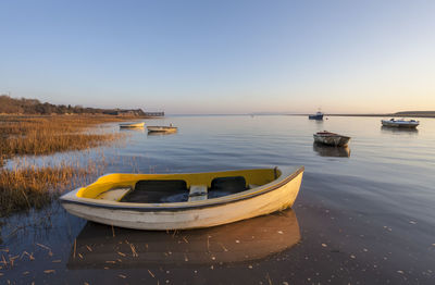 Boats moored in lake against sky during sunset