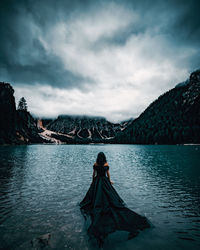 Rear view of woman looking at lake against mountain