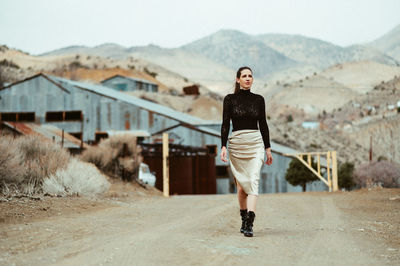 Full length portrait of young woman standing on mountain