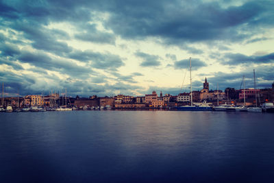 Buildings by sea against sky at dusk