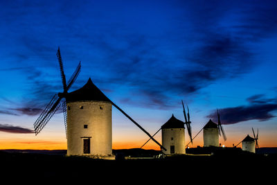 Low angle view of traditional windmill against sky at sunset