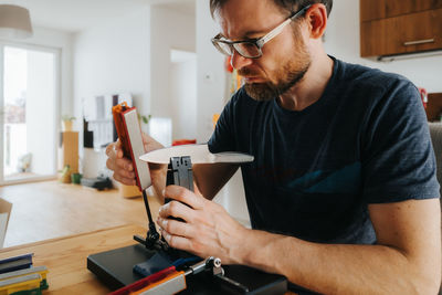 Midsection of man sharpening knife with whetstone decice