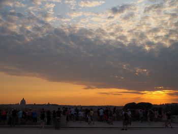 People walking against orange sky