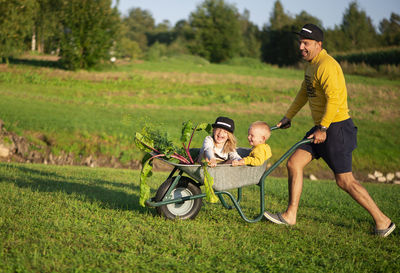 Happy dad rides his kids in a wheelbarrow