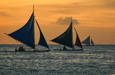 Sailboat sailing on sea against sky during sunset