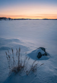 Scenic view of snow covered land against sky during sunset