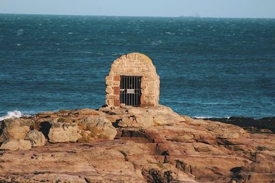 Scenic view of rock formation by sea against sky