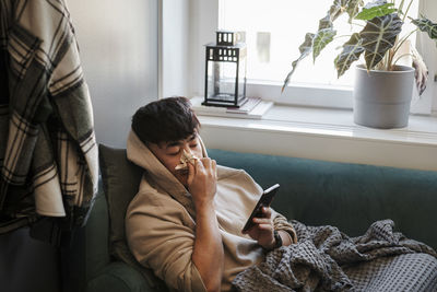 Ill man on sofa using cell phone