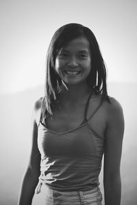 Portrait of a smiling young woman standing against white background