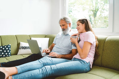 Young woman using laptop while sitting on sofa at home