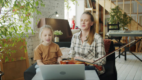 Mother teaching violin to daughter at home