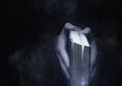 Close-up of hands holding book against blurred background