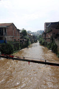 Water flowing in city against sky