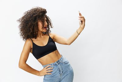 Young woman with arms raised standing against white background