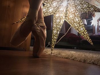 Low section of woman with umbrella standing on floor at home