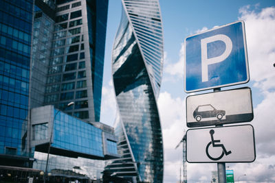 Low angle view of road sign against modern buildings in city