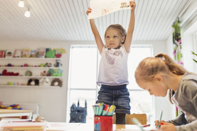 Little girl showing drawing in classroom