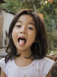 Portrait of cute girl sticking out tongue while standing outdoors