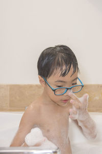 Shirtless boy bathing in bathtub at home