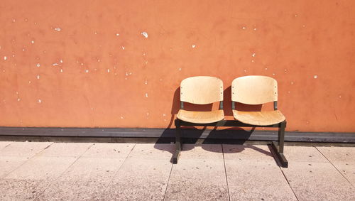 Empty chairs against orange wall