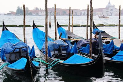 Traditional gondolas moored by wooden post in sea