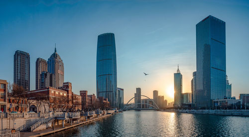 View of skyscrapers by river against buildings in city