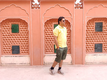 Full length of man standing against yellow wall