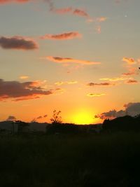 Scenic view of silhouette field against orange sky