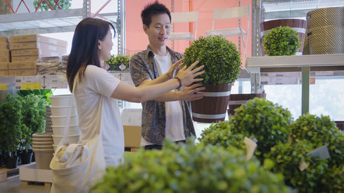 Portrait of young woman standing against plants