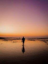 Silhouette of man at beach against sky during sunset