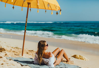 Woman lying on shore at beach against sky