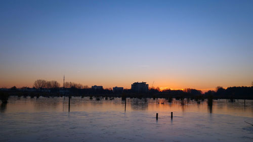 Scenic view of silhouette city against clear sky during sunset